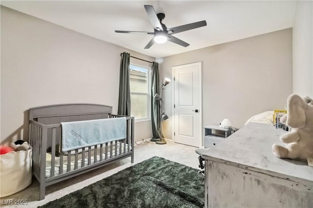 bedroom with a nursery area, ceiling fan, and light carpet