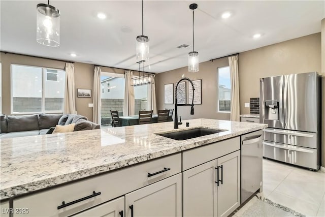 kitchen featuring pendant lighting, sink, light tile patterned floors, appliances with stainless steel finishes, and light stone countertops