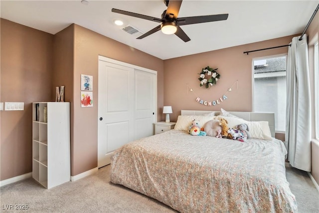 bedroom featuring light colored carpet, a closet, and ceiling fan