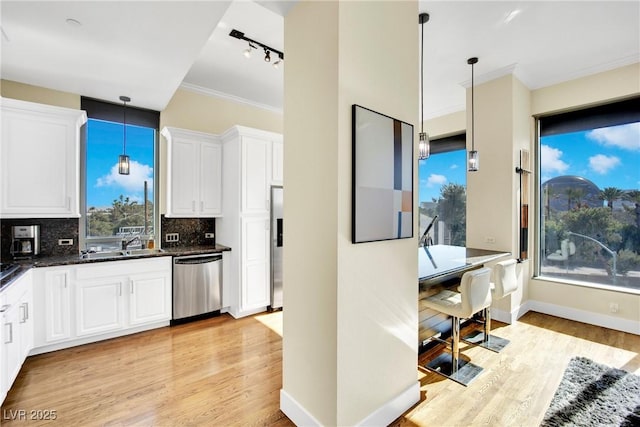 kitchen with tasteful backsplash, stainless steel appliances, decorative light fixtures, and white cabinets