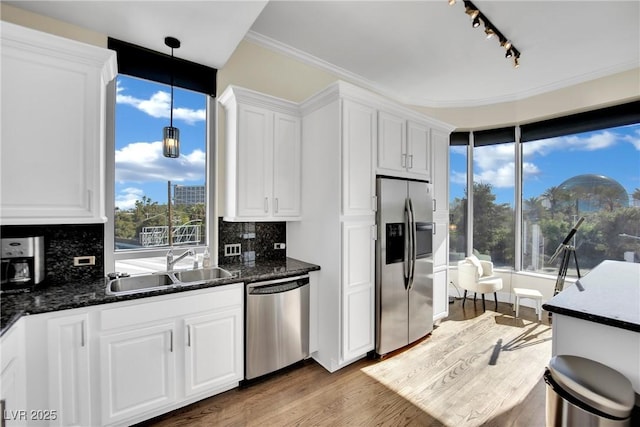 kitchen featuring sink, white cabinetry, hanging light fixtures, stainless steel appliances, and light hardwood / wood-style floors