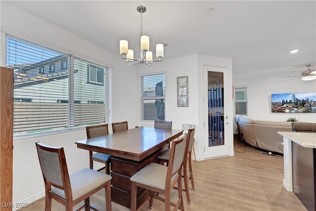 dining space with ceiling fan with notable chandelier and light hardwood / wood-style floors