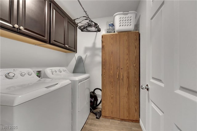 laundry room featuring washer and clothes dryer, light hardwood / wood-style floors, and cabinets