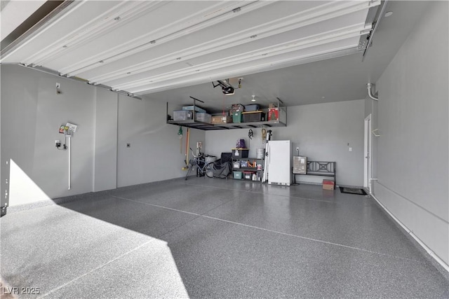 garage featuring white refrigerator and a garage door opener