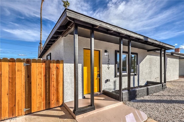 property entrance with fence and stucco siding