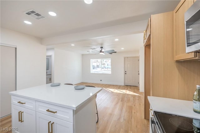 kitchen featuring visible vents, white cabinets, light countertops, appliances with stainless steel finishes, and a center island