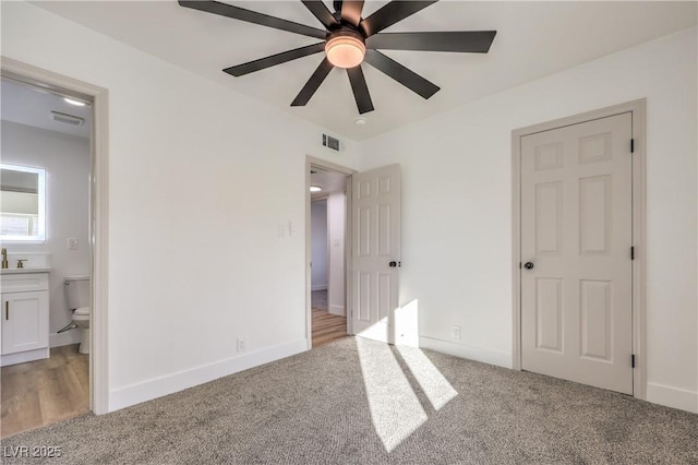 unfurnished bedroom with carpet floors, ensuite bath, visible vents, and baseboards