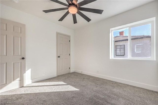 carpeted empty room with ceiling fan and baseboards