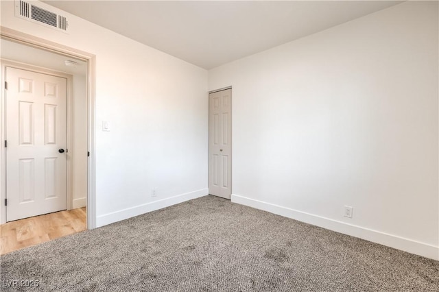 carpeted spare room featuring visible vents and baseboards