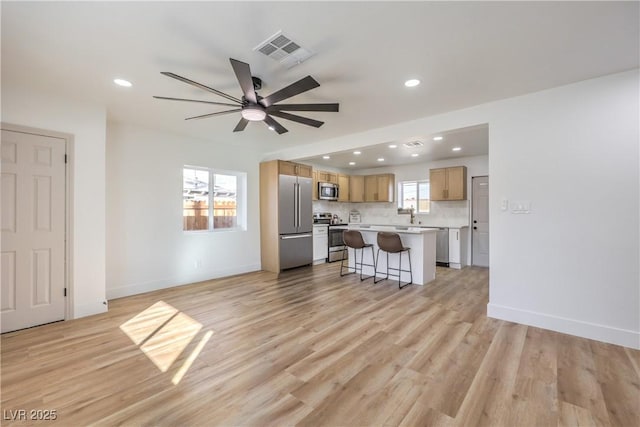 unfurnished living room featuring light wood finished floors, recessed lighting, visible vents, ceiling fan, and a sink