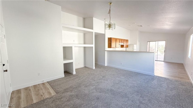 unfurnished living room with light carpet, vaulted ceiling, and a textured ceiling