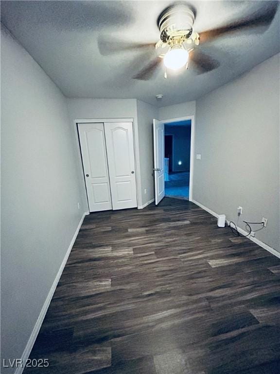 unfurnished bedroom featuring ceiling fan, dark wood-type flooring, and a closet