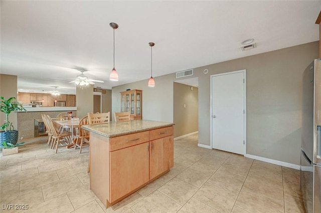 kitchen featuring decorative light fixtures, ceiling fan, light stone counters, light brown cabinets, and light tile patterned flooring