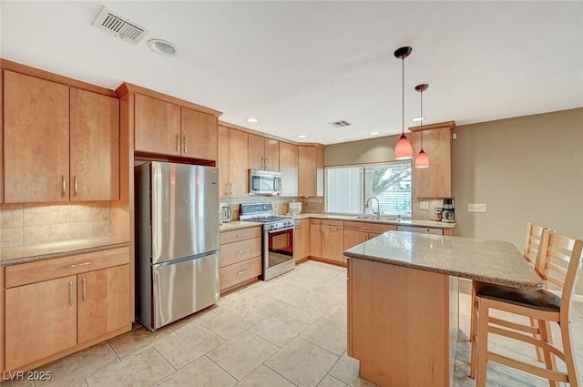 kitchen featuring appliances with stainless steel finishes, sink, backsplash, decorative light fixtures, and light stone countertops