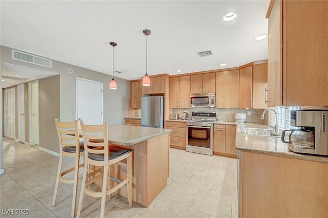 kitchen featuring sink, hanging light fixtures, light stone countertops, and stainless steel appliances