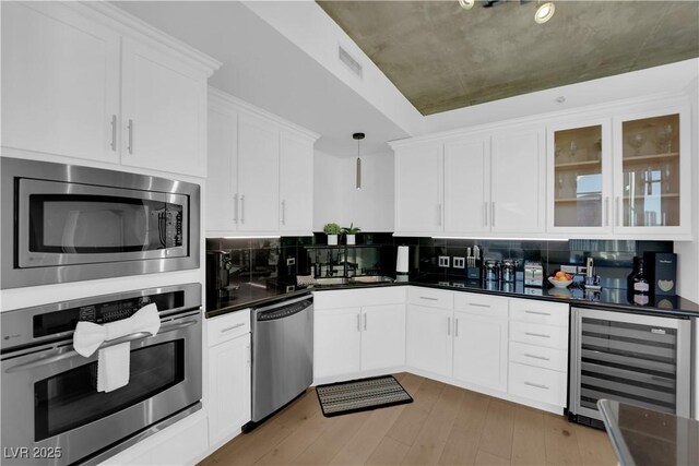 360 E Desert Inn Rd Unit 604, Las Vegas, NV 89109 - kitchen featuring appliances with stainless steel finishes, beverage cooler, dark countertops, white cabinets, and light wood finished floors