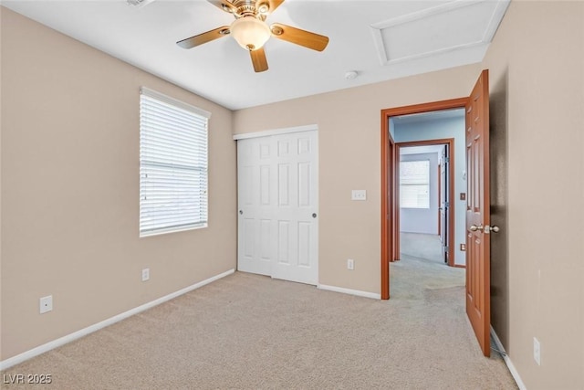 unfurnished bedroom with ceiling fan, light colored carpet, a closet, and multiple windows