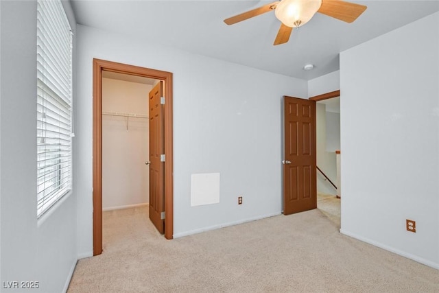 unfurnished bedroom featuring ceiling fan, a closet, a spacious closet, and light carpet