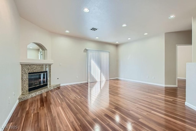 unfurnished living room with visible vents, baseboards, recessed lighting, a fireplace, and wood finished floors