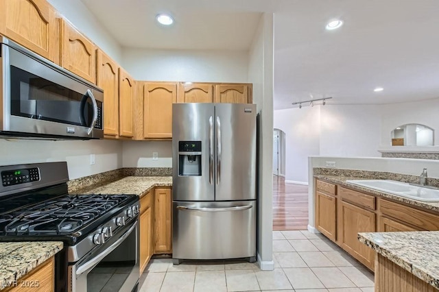 kitchen with light tile patterned floors, light stone counters, recessed lighting, stainless steel appliances, and a sink