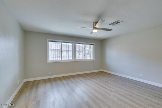 unfurnished room featuring a ceiling fan, visible vents, light wood-style flooring, and baseboards