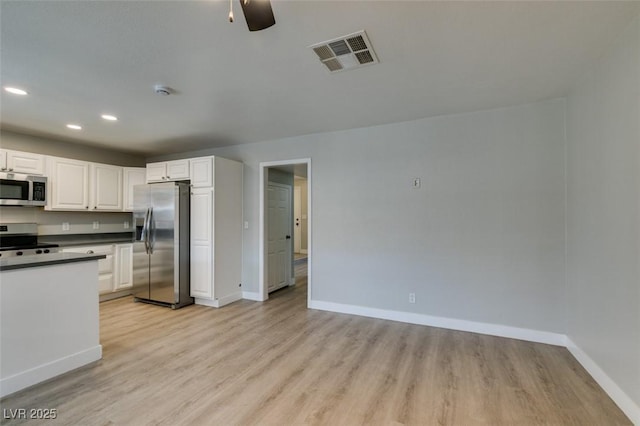 kitchen with stainless steel appliances, visible vents, light wood-style floors, white cabinets, and baseboards