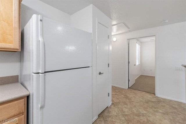 kitchen with white refrigerator, light tile patterned flooring, and light brown cabinets