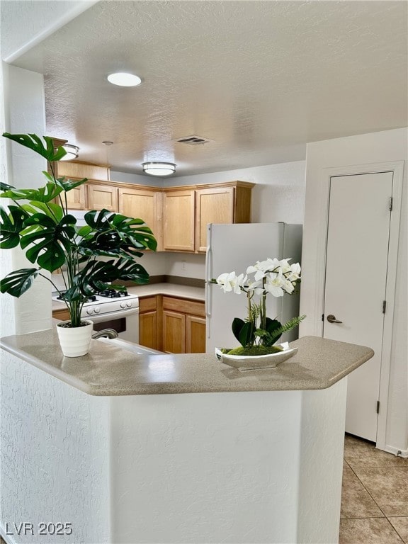 kitchen featuring white appliances, kitchen peninsula, and light brown cabinets