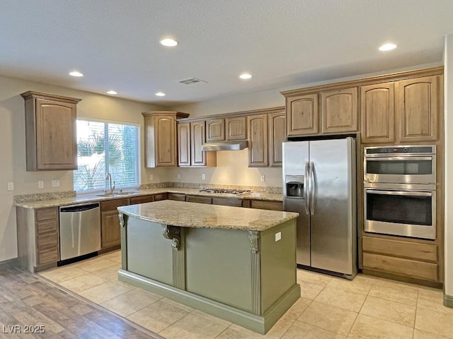 kitchen with sink, light stone counters, a center island, light tile patterned floors, and stainless steel appliances