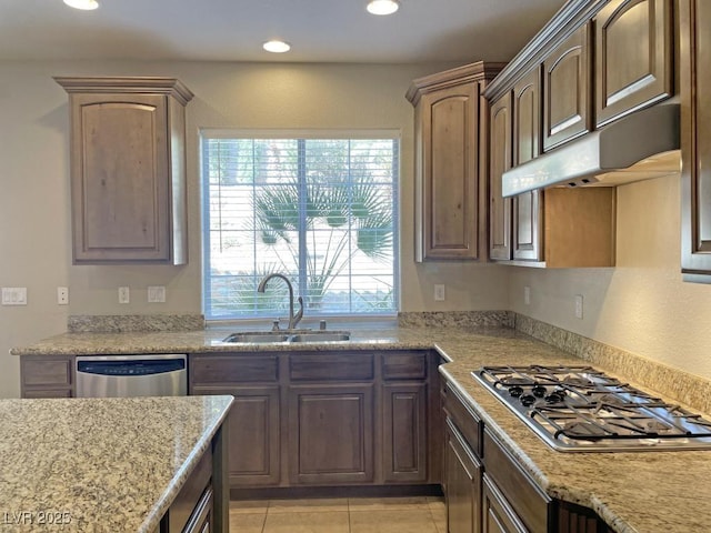 kitchen with light stone counters, appliances with stainless steel finishes, sink, and light tile patterned floors