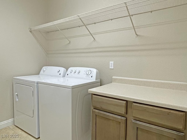 clothes washing area with separate washer and dryer and cabinets