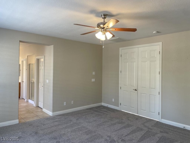 unfurnished bedroom featuring light carpet, a textured ceiling, ceiling fan, and a closet