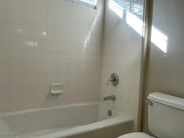 bathroom featuring tiled shower / bath and toilet