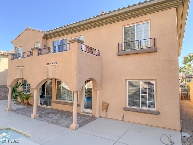 rear view of property featuring a patio and a balcony