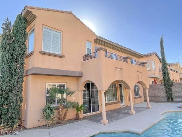 rear view of property featuring a fenced in pool and a patio