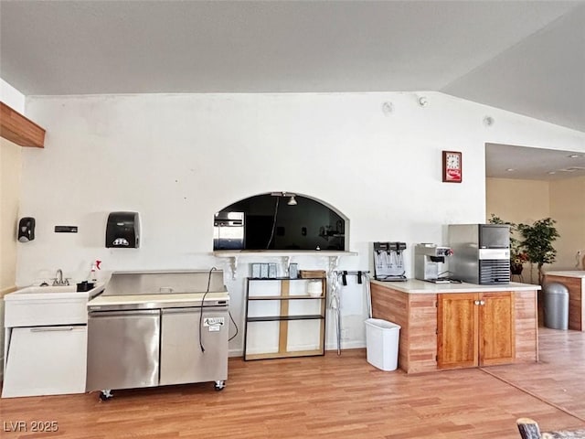 kitchen featuring lofted ceiling, sink, and light wood-type flooring