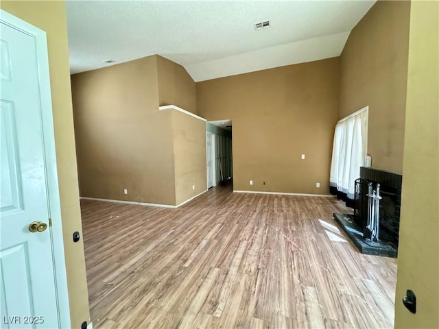 unfurnished living room featuring high vaulted ceiling and light hardwood / wood-style floors