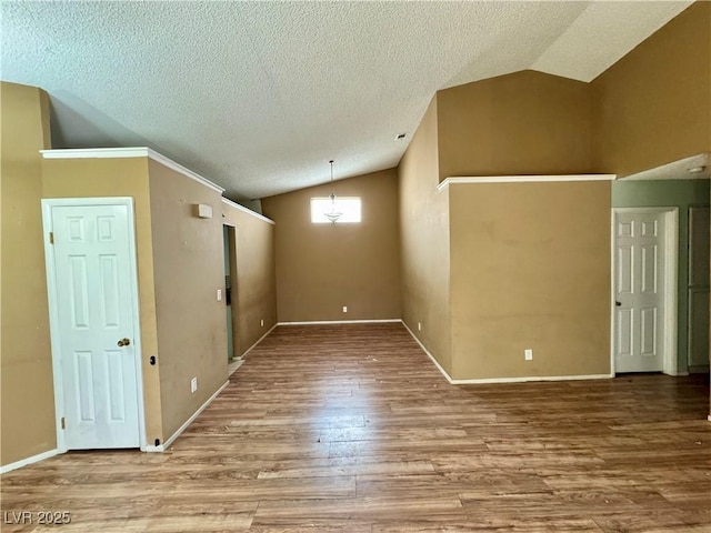 empty room featuring hardwood / wood-style flooring, vaulted ceiling, and a textured ceiling