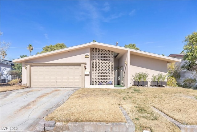 mid-century modern home with a garage, driveway, and stucco siding