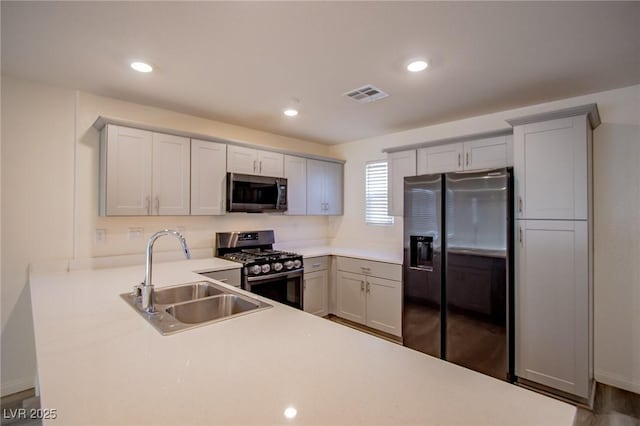 kitchen featuring sink, hardwood / wood-style floors, kitchen peninsula, and appliances with stainless steel finishes