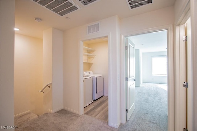 hallway featuring light colored carpet and washer and clothes dryer