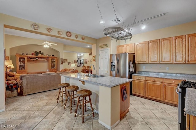 kitchen with sink, stainless steel appliances, light stone countertops, an island with sink, and a kitchen bar