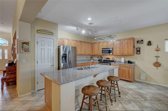 kitchen featuring a breakfast bar, sink, a center island with sink, light tile patterned floors, and stainless steel appliances