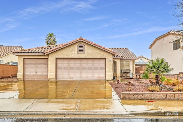 mediterranean / spanish house featuring a garage, concrete driveway, a tiled roof, fence, and stucco siding