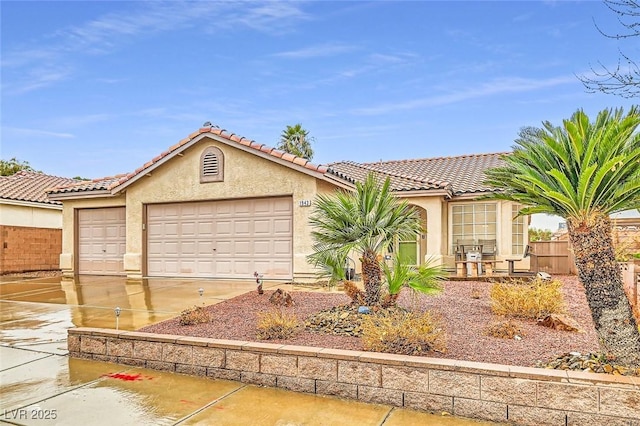 mediterranean / spanish home featuring stucco siding, concrete driveway, fence, a garage, and a tiled roof