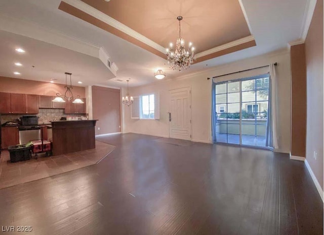 unfurnished living room with an inviting chandelier, dark hardwood / wood-style floors, and a raised ceiling