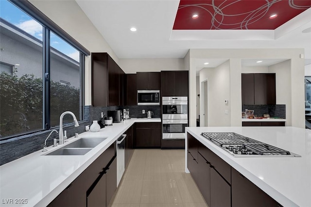 kitchen featuring dark brown cabinetry, sink, a raised ceiling, and appliances with stainless steel finishes