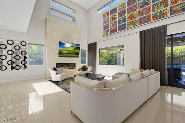 tiled living room with a tile fireplace, a healthy amount of sunlight, and a towering ceiling