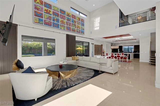 living room with a healthy amount of sunlight, light tile patterned floors, and a towering ceiling