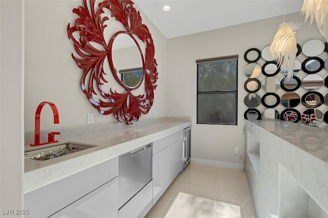 interior space with white cabinetry, dishwasher, sink, light tile patterned floors, and light stone countertops